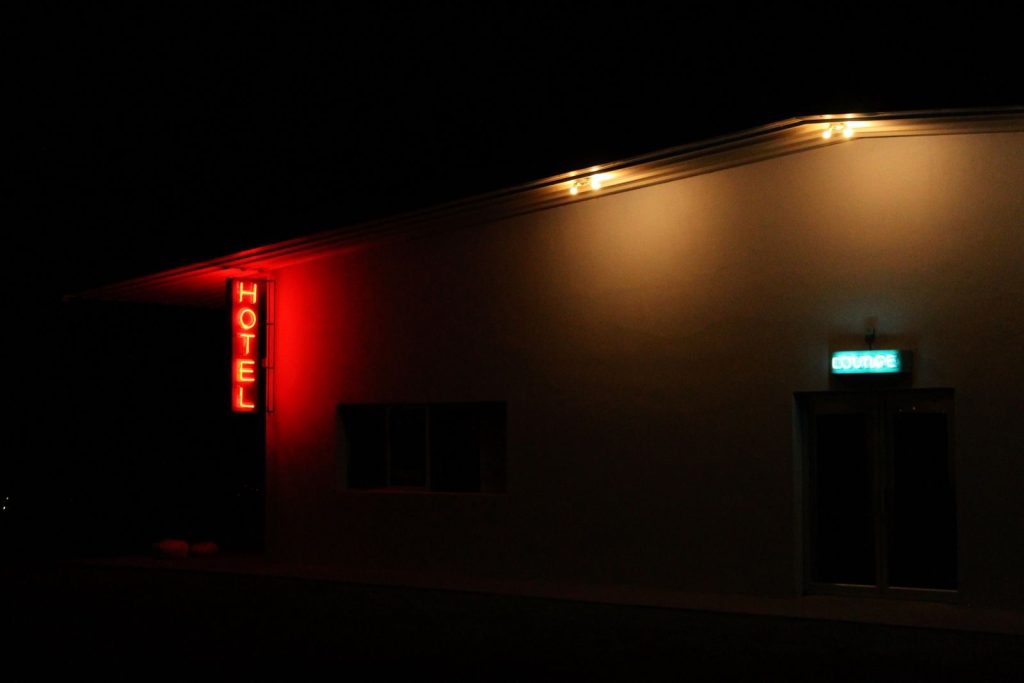 Exterior of an illuminated hotel with neon signs at night in Marfa, Texas.