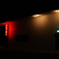 Exterior of an illuminated hotel with neon signs at night in Marfa, Texas.