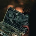 A hand holding a book with mystical illustrations, captured in artistic lighting.