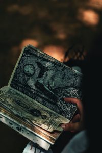 A hand holding a book with mystical illustrations, captured in artistic lighting.