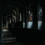 Dimly lit, eerie interior of an abandoned church with gothic arches and shadows.
