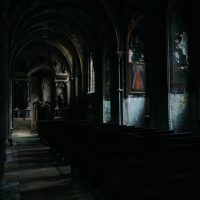 Dimly lit, eerie interior of an abandoned church with gothic arches and shadows.