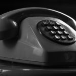 Close-up of a vintage rotary telephone in monochrome, symbolizing retro communication.