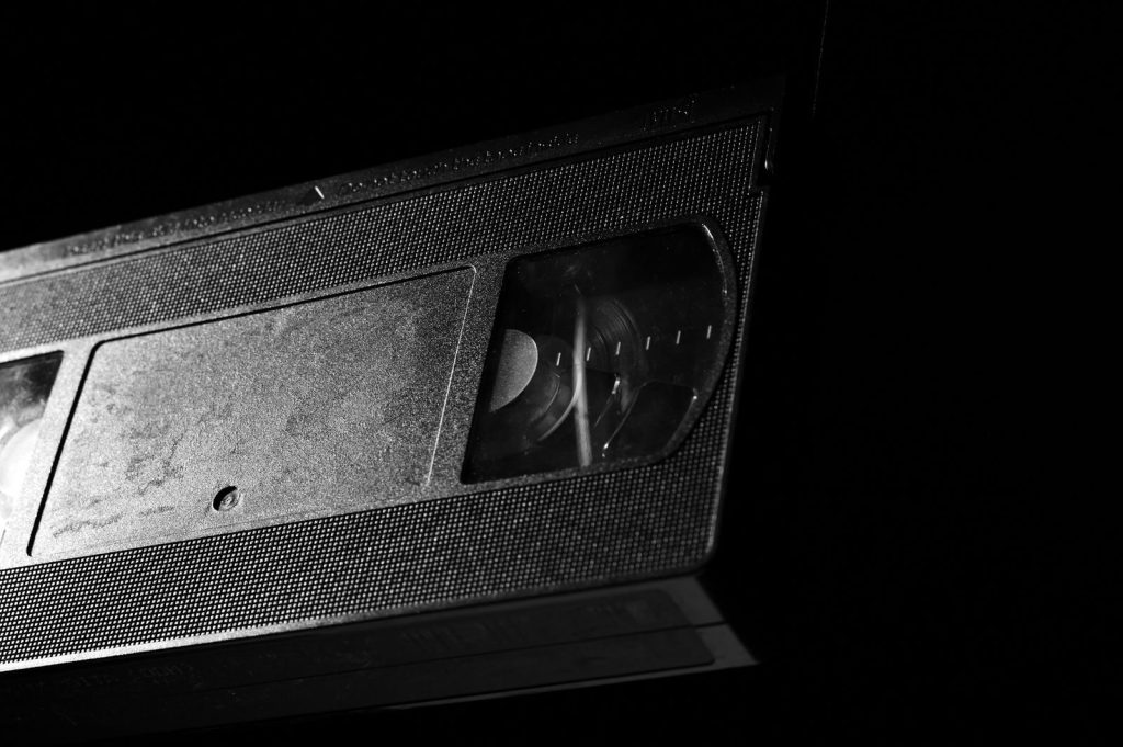 High-contrast close-up of a retro VHS tape against a dark background.