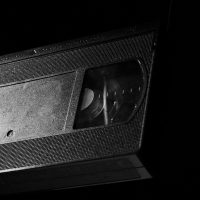 High-contrast close-up of a retro VHS tape against a dark background.