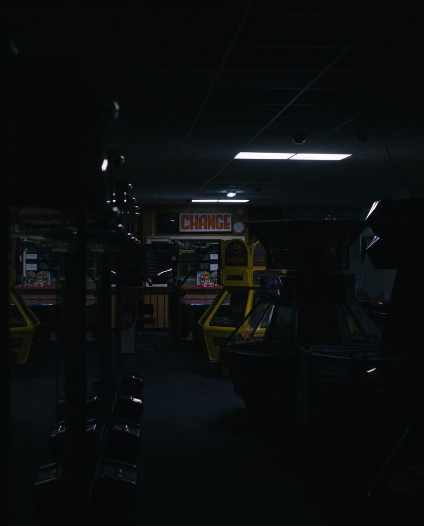 A dark and eerie arcade featuring retro game machines under a "CHANGE" sign.