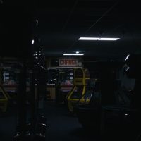 A dark and eerie arcade featuring retro game machines under a "CHANGE" sign.
