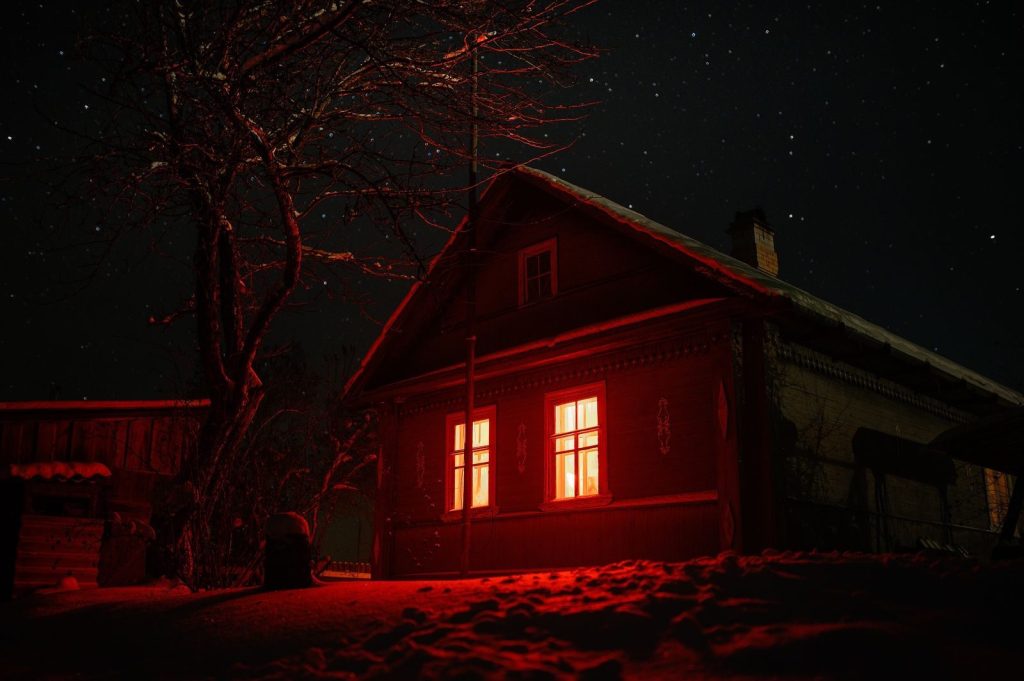 Eerie haunted house with red glowing windows under a starry night sky, perfect for spooky themes.
