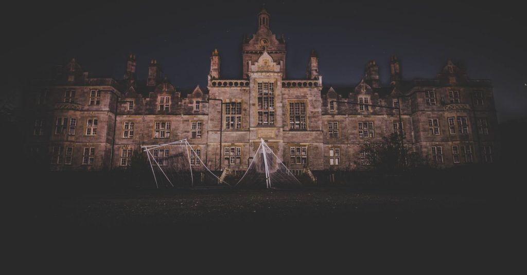 A nighttime photograph of an eerie, abandoned mansion in Wales, exuding a spooky atmosphere.