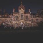A nighttime photograph of an eerie, abandoned mansion in Wales, exuding a spooky atmosphere.