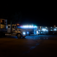 Two brightly lit trucks parked in an urban area at night, showcasing their vibrant lights.