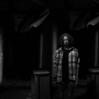 Dramatic black and white portrait of a man in an eerie, abandoned space. Captures mystery and solitude.