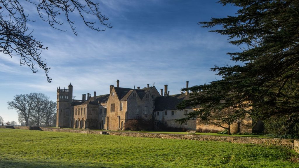 A picturesque view of Lacock Abbey surrounded by lush greenery in Lacock, England.