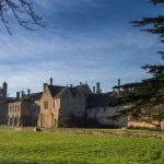 A picturesque view of Lacock Abbey surrounded by lush greenery in Lacock, England.