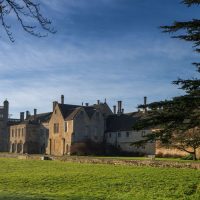 A picturesque view of Lacock Abbey surrounded by lush greenery in Lacock, England.