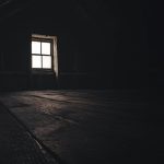 a dark room with a window and a wooden floor