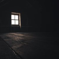 a dark room with a window and a wooden floor
